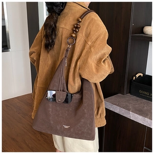 Detail of dark brown faux leather tote bag featuring unique wooden bead strap and sunglasses loop