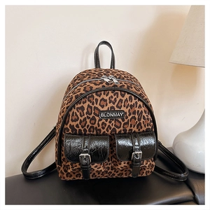 Détail d'un sac à dos léopard avec poches en vernis noir et boucles métalliques