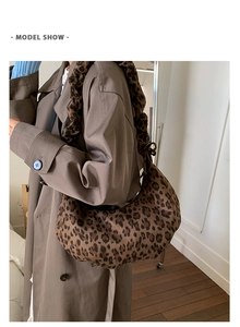 Close-up of leopard print crescent bag with ruffled strap styled on a trench coat