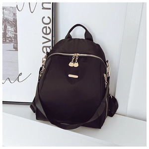Detail of black oxford backpack with golden heart-shaped zippers and brand metal plate
