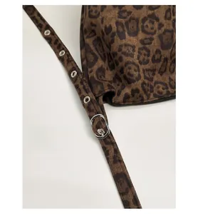 Detail of adjustable leopard print bag strap with silver metal eyelets and suede texture