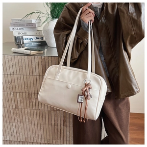 Detail of cream leather tote bag with long dual straps and a decorative horse charm