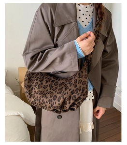 Detailed view of the leopard print crossbody crescent bag worn with a brown coat