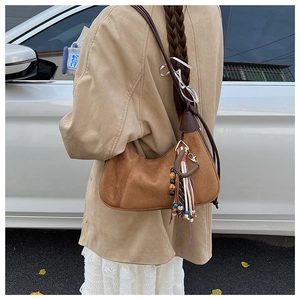 Détail du sac dumpling en daim marron vintage avec pompons ethniques et perles déco