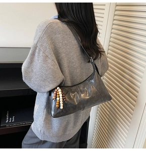 Detail of dark grey hobo bag with vintage beaded tassel and premium leather texture