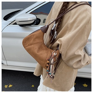 Détail d'un sac hobo en daim marron avec pendentif à pampilles de style bohème