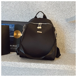 Detail of black oxford backpack showing double silver zippers and metal chain decoration