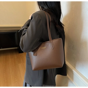Détail d'un sac cabas marron à motif litchi avec logo doré et bandoulière