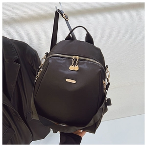 Close-up of black nylon backpack featuring gold zippers and metallic brand nameplate