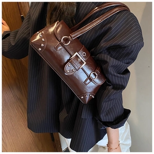Détail d'un sac à bandoulière en cuir marron brillant avec rivets et boucle en métal