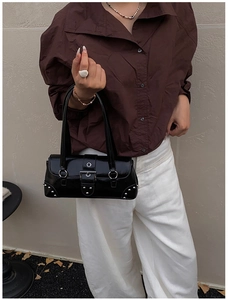 Détail du sac sous le bras en cuir ciré noir brillant avec rivets et boucle métallique