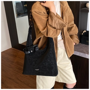 Détail du sac hobo en daim noir avec bandoulière en perles de bois et logo blanc élégant