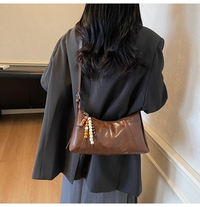 Detail of vintage brown faux leather shoulder bag with decorative wooden bead charm