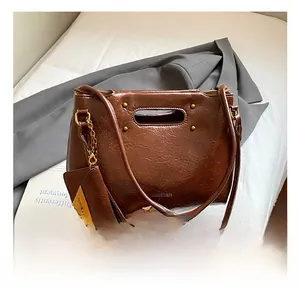 Detail of vintage brown tote bag with oily PU leather texture and brass rivet accents