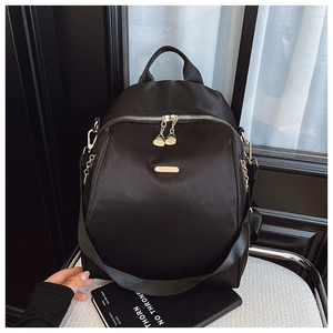 Detail of black oxford backpack with gold metal zippers and brand logo on a soft chair