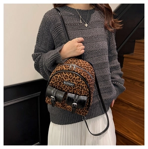 Détail du sac à dos léopard montrant des poches à boucles noires et zips argentés
