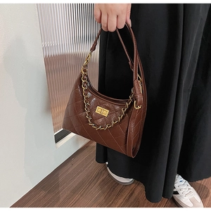 Détail du sac hobo marron foncé avec motif matelassé et poignée en chaîne dorée épaisse