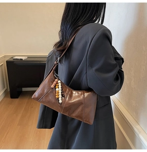 Close-up of brown vintage leather shoulder bag with decorative colorful beaded tassel