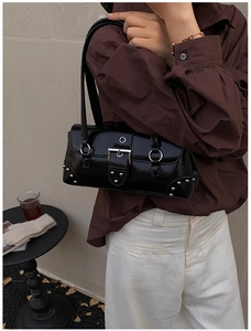 Détail du sac baguette en cuir verni noir vintage avec rivets argentés et boucles