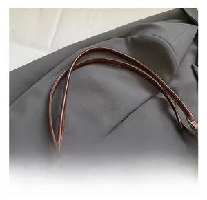 Detail of vintage brown textured leather handbag with gold rivets and slender handles