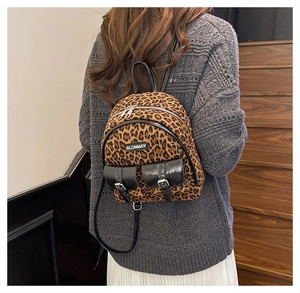Détail du mini sac à dos léopard avec poches en cuir verni noir et étiquette de la marque