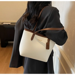 Détail du sac cabas blanc et marron avec étiquette en cuir sur l'épaule du mannequin
