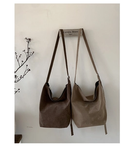 Hanging minimalist suede tote bags in brown and khaki on a vertical hook