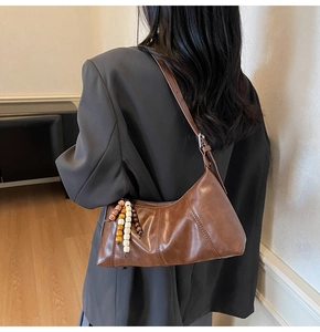 Detail of dark brown vintage hobo bag with colorful wooden bead tassel and metal zipper