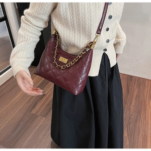 Gros plan du sac en cuir matelassé bordeaux avec chaîne dorée et fermoir rotatif