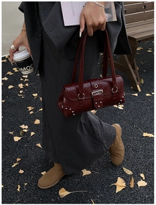Gros plan du sac baguette en cuir ciré bordeaux avec rivets et boucles argentés