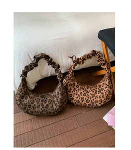 Detail of leopard print half-moon bags with gathered ruched straps on wooden floor