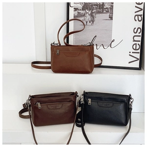 Close-up of textured PU leather crossbody bags in caramel, dark brown, and black colors