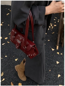 Sac sous le bras en cuir ciré rouge foncé avec rivets argentés dans un décor d'automne