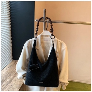 Détail du sac en daim noir minimaliste avec une bandoulière artistique en perles de bois