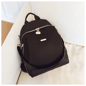 Close-up of black oxford backpack with golden metal logo and premium zipper detail