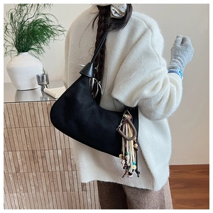 Vue détaillée du sac demi-lune en daim noir avec pompons boho colorés et perles bois