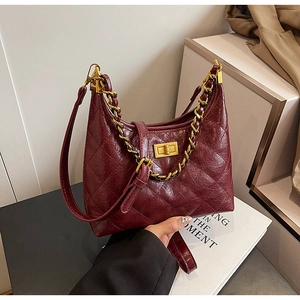 Détail du sac bandoulière matelassé rouge vin avec chaîne dorée et fermoir métal
