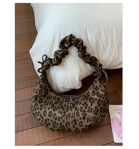 Detail of leopard print crescent bag with stylish ruched strap in a cozy home setting