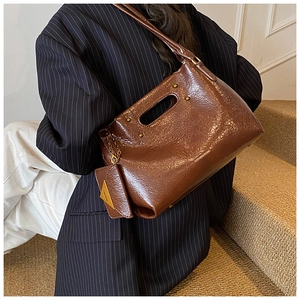 Macro detail of brown glossy leather handbag with golden chain and mini triangle pouch
