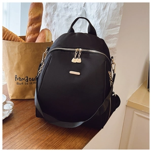 Detailed view of black oxford backpack fabric with golden heart-shaped zipper on wooden table