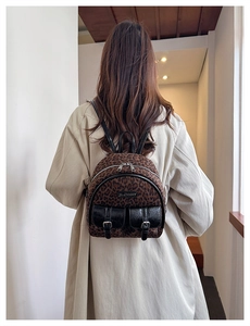 Détail du mini sac à dos léopard montrant la poche à rabat en cuir et la plaque en métal