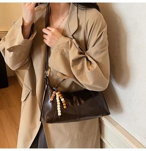 Detail of dark brown vintage dumpling bag with leather strap and decorative wood beads