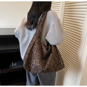 Detailed shot of large leopard print hobo bag worn by a model in a cozy interior