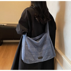 Detail view of large blue tote bag with denim texture and minimalist black logo patch