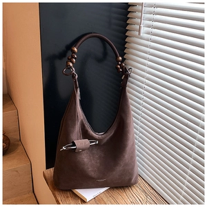 Dettaglio borsa tote in pelle scamosciata marrone con manico in perline di legno
