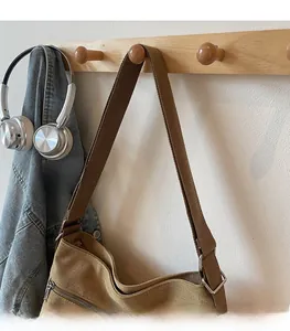 Detail of khaki canvas tote bag featuring brown woven strap and smooth metal zipper closure