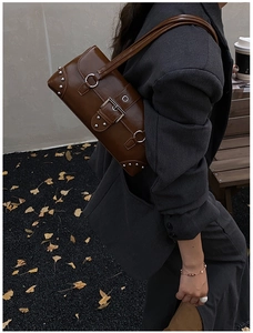 Détail du sac sous le bras en cuir marron vintage avec rivets argentés et boucle métal