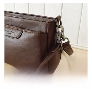 Detailed macro view of the detachable vintage metal hook on the brown leather bag strap