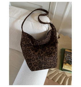 Macro shot of dark brown leopard print hobo bag with suede texture on a white sofa
