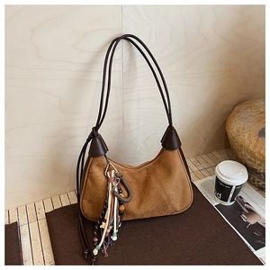 Détail d'un sac demi-lune en daim marron avec pompon vintage et de longues lanières